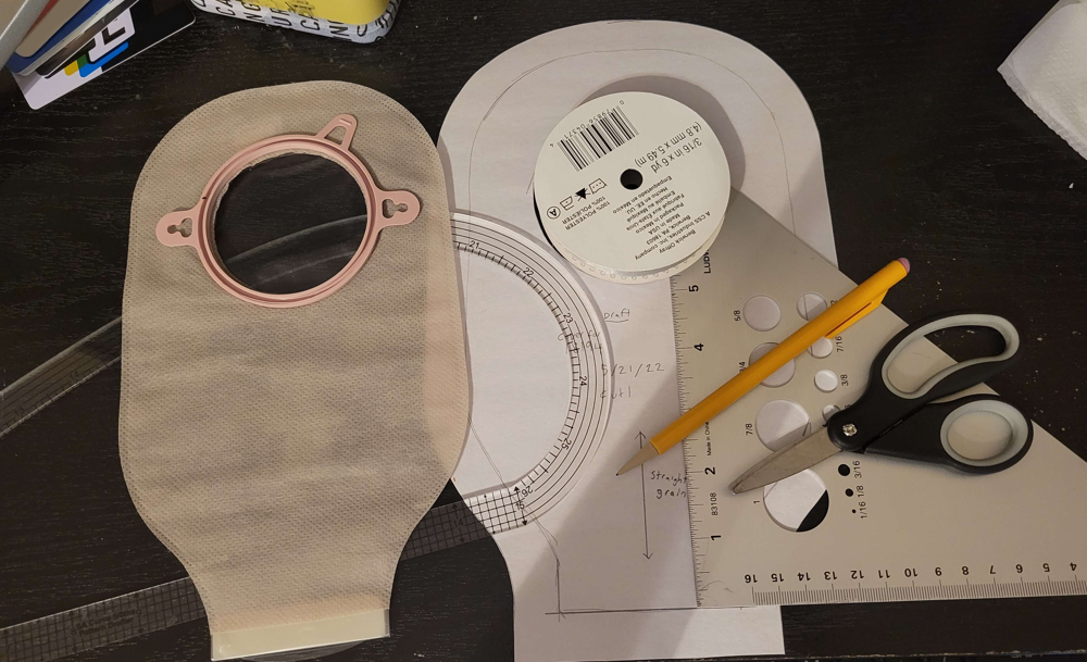 (image: An ostomy bag, a seam allowance curve, a drafting triangle, ribbon spool about the same size as the ostomy bag's opening, scissors, and pencil.)